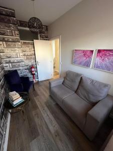 een woonkamer met een bank en een stenen muur bij Junqueira76 Guesthouse in Póvoa de Varzim