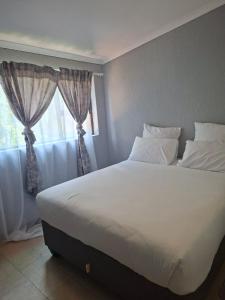 une chambre avec un grand lit blanc avec une fenêtre dans l'établissement Number 8, à Maseru 6 autres photos