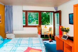 a bedroom with a bed and a desk and windows at Hotel An der Sauer in Minden