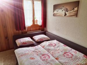 two beds in a small room with red curtains at Apartment Gemütliche FeWo by Interhome in Innertkirchen