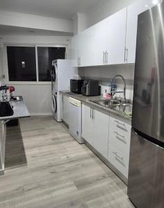 een keuken met witte kasten, een wastafel en een koelkast bij O Lar da Elisa in Bicas