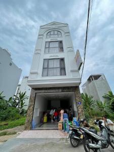 ein weißes Gebäude, vor dem Menschen stehen in der Unterkunft Hotel Hoàng Phúc in Vũng Tàu