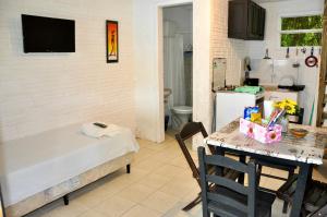 una camera con letto e tavolo e una cucina di Pousada Pantera do Rosa a Imbituba