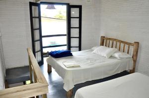 una camera da letto con due letti e una finestra di Pousada Pantera do Rosa a Imbituba Altre 14 foto