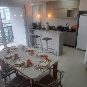 a table with plates and cups on it in a kitchen at Apto 3 quartos Centro Torres RS in Torres