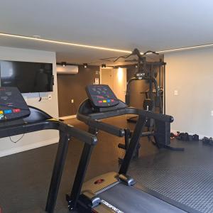 a gym with a treadmill and a flat screen tv at Apto 3 quartos Centro Torres RS in Torres