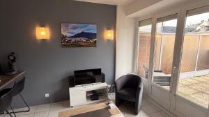 a living room with a tv and a table and chairs at Appartement centre ville et terrasse in Brive-la-Gaillarde