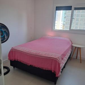 a bedroom with a pink bed and a window at Apto 3 quartos Centro Torres RS in Torres