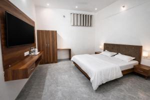 een slaapkamer met een bed en een flatscreen-tv bij Takery Resort in Chittaurgarh