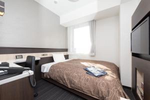 a hotel room with a bed and a flat screen tv at Sanco Inn Tsu Ekimae in Tsu