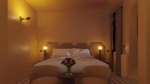 ein Schlafzimmer mit einem Bett mit 2 Stühlen und einer Vase aus Blumen in der Unterkunft Latroupe Hotel Le Berger in Brüssel