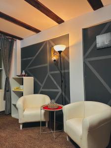 ein Zimmer mit zwei Stühlen und einem Tisch und einer Lampe in der Unterkunft Casa Oriana in Predeal + 1 Foto