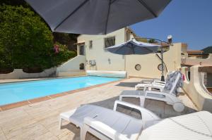 een groep stoelen en een parasol naast een zwembad bij Villa la Chiosella in Valle-di-Mezzana
