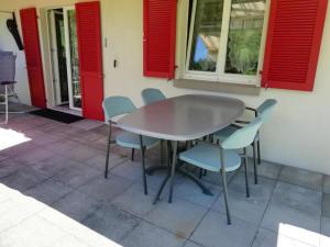 a table and chairs on a patio with red shutters at Apartment Bella Vista by Interhome in Sörenberg