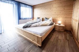 een slaapkamer met een groot bed in een houten muur bij Oberhof Apt Lärchenwald in Vallarga