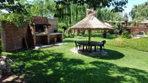 une table de pique-nique et un parasol en paille dans une cour dans l'établissement Cabañas El Sauce, à Albardón 11 autres photos