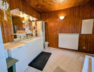 een grote badkamer met houten wanden en een witte wastafel bij Chambre Chez Lou in Bucey-lès-Gy