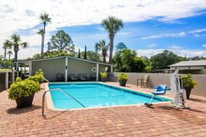 a swimming pool with a patio and palm trees at Best Western Starke in Starke