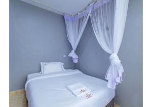 a bedroom with a white bed with white curtains at The VIP Luxury CBD in Kisumu