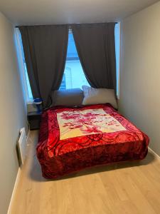 una camera da letto con un letto con un piumone rosso e una finestra di Borggata a Oslo