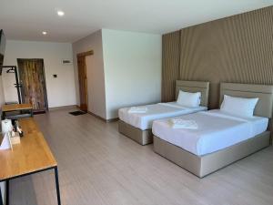 a hotel room with two beds and a desk at Madee House - มาดีเฮ้าส์ in Ban Ao Yang