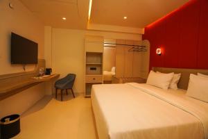 een hotelkamer met een bed, een bureau en een televisie bij Hotel Harriet in Rāmeswaram