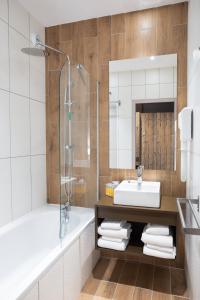 een badkamer met een wastafel, een bad en een douche bij SOWELL Family Valfrejus in Valfréjus