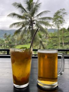 twee drankjes op een tafel met een palmboom op de achtergrond bij Sinharaja Eliphinity Hotel and Restaurant in Deniyaya