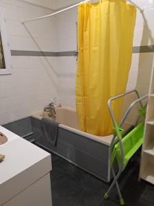 a bathroom with a tub with a yellow shower curtain at Grand appart 2 chambres - max 6 pers in Vrigne-aux-Bois