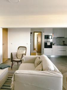 a living room with a white couch and a kitchen at Cantinho de Belmonte in Belmonte
