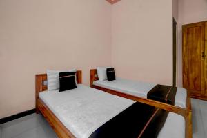 two twin beds in a room withthritisthritislictslictslicts at OYO 94899 Homestay Syariah Near UPN in Medokanayu