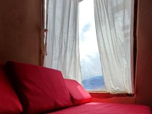 een slaapkamer met een raam en een bed met rode kussens bij Cabañas Mallma in Tilcara