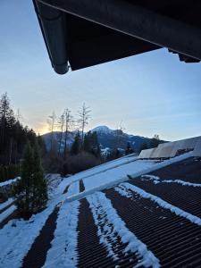 a snow covered roof of a house with mountains in the background at Glory Igls Lodge in Innsbruck