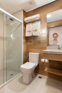 ein Badezimmer mit Toilette und Glasdusche in der Unterkunft Wyndham Natal Pitangui Praia in Extremóz