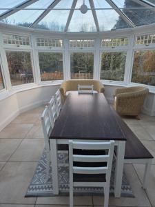 een serre met een tafel, stoelen en ramen bij Comfy Home- Coley Park in Reading