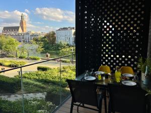 ein Tisch mit Stühlen und ein Balkon mit Blick auf eine Stadt in der Unterkunft Wroclove Apartments in Breslau