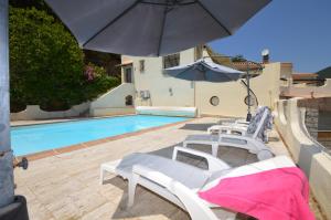 een zwembad met 2 ligstoelen en een parasol bij Villa la Chiosella in Valle-di-Mezzana