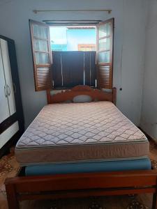 Bett in einem Zimmer mit 2 Fenstern in der Unterkunft Casa no Centro da cidade! in Goiás