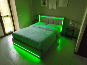 un lit vert dans une chambre éclairée en vert dans l'établissement Burro e Salvia Home, à Bergame