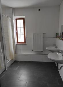 un bagno bianco con due lavandini e una finestra di Gasthaus Wipfler a Villenbach