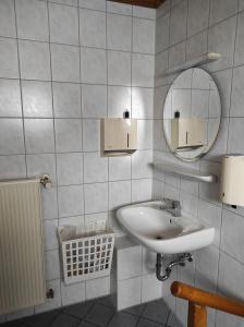 un bagno bianco con lavandino e specchio di Gasthaus Wipfler a Villenbach