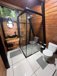 a bathroom with a toilet and a glass shower at Chalé das pedras in Massaranduba +12 photos
