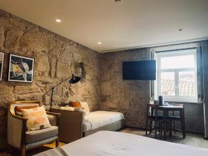 een slaapkamer met een bed, een stoel en een tv bij Oca Ribeira do Porto AT in Porto