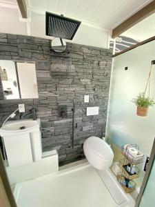 a bathroom with a white toilet and a stone wall at Casa Azul Experience at The Perry in Key West