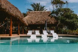 a group of white chairs sitting in a swimming pool at Punta Mango Villas in La Periquera