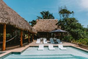 un resort con piscina attrezzata con sedie e ombrelloni di Punta Mango Villas a La Periquera