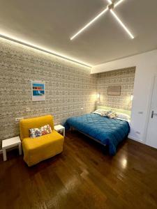 a bedroom with a bed and a yellow chair at Old Town Nest in Civitavecchia in Civitavecchia