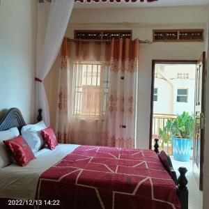 une chambre avec un lit avec des oreillers rouges et une fenêtre dans l'établissement Vine Inn Mbarara, à Mbarara