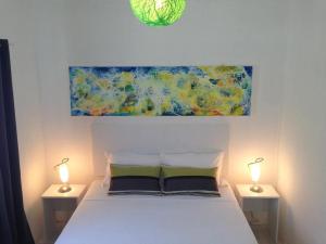 een slaapkamer met een wit bed met twee lampen bij La Oursha Apartment in Pointe aux Biches