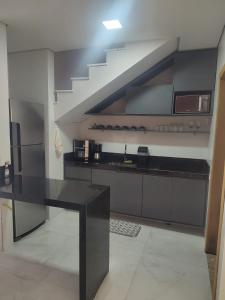 a kitchen with a black counter top and a staircase at Casa com 3 suítes em Juquehy in São Sebastião
